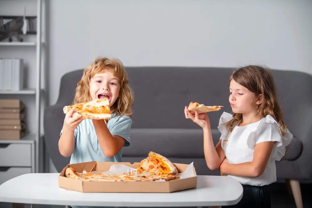 děti jedí pizzu v obýváku u televize